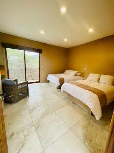 a bedroom with two beds and a large window at Villas Ecuestre Hotel Tepoztlán in Tepoztlán