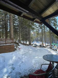 a patio with a table and snow covered ground at Apartman sa terasom Vila Mina Kopaonik in Kopaonik +9 photos