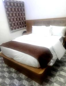 a bedroom with a large bed with white sheets and pillows at JACKSON'S COURT AND APARTMENT in Rubuchi