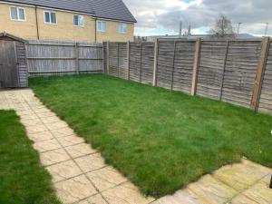 a backyard with a fence and green grass at LUXURY 3 BED HOME with MULTIPLE FREE PARKING BAYS Early Check-in Late Check- Out Allowed in West Thurrock