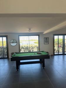 a pool table in a large room with windows at Chez Diarra in Saint-Louis