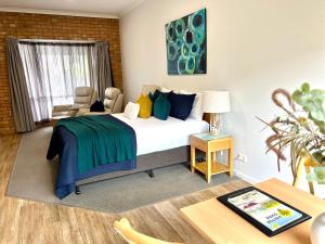 um quarto com uma cama, uma cadeira e uma mesa em Coastal Waters Motor Inn em Lakes Entrance