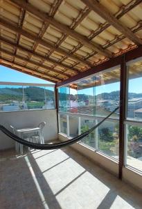 a room with a hammock on a balcony with windows at Suítes Independentes Praia dos Anjos in Arraial do Cabo