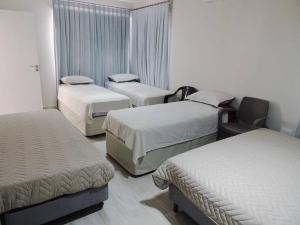 ein Hotelzimmer mit 3 Betten und einem Stuhl in der Unterkunft Casa Ola, lugar de descanso en Salta! in Vaqueros