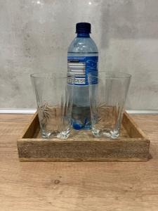 een fles water en twee glazen op een houten blad bij Nowoczesny apartament z przestronną łazienką in Stalowa Wola