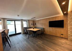 a dining room with a table and a tv on a wall at Luxury Apartment, Kaisergebirge in Ebbs