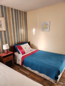 a bedroom with a bed with a blue blanket and a table at Viña Excelente, 1 cuadra Av Sn Martin y la playa in Viña del Mar