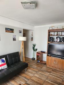 uma sala de estar com um sofá preto e uma televisão de ecrã plano em Viña Excelente, 1 cuadra Av Sn Martin y la playa em Viña del Mar