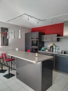 a kitchen with a large table and red accent wall at Appartement standing proche Disney et Paris in Pomponne