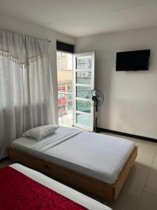 um quarto com uma cama grande e uma janela em Hotel El Jardín Cafetero Armenia em Armênia