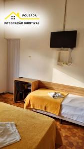 a hotel room with two beds and a desk at Pousada Integração Buritizal in Buritizal +18 photos