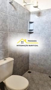 a bathroom with a toilet and a wall at Pousada Integração Buritizal in Buritizal