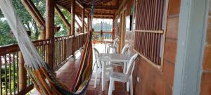a porch with a hammock and a table and chairs at Finca Hotel Villa Ilusión in Pereira