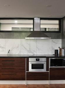 Large Bright Modern Loft Apt - Central Location - Suitable for Families and Groups في Narrabundah: مطبخ مع موقد وميكروويف