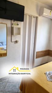 a room with a bed and a mirror and a tv at Pousada Integração Buritizal in Buritizal