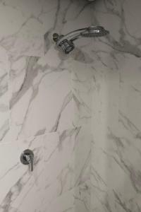 a white marble shower stall with a faucet at Large Loft Modern Apt for Big Groups in Narrabundah