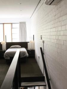 um quarto com 2 camas e uma parede de tijolos em Large Bright Modern Loft Apt - Central Location - Suitable for Families and Groups em Narrabundah