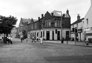 a black and white photo of a street with people crossing the street at Coorie Doon - Aparthotel - Troon in Troon