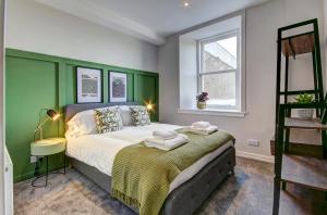um quarto com uma cama grande e uma cabeceira verde em Coorie Doon - Aparthotel - Troon em Troon