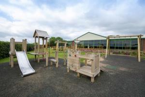 un parque infantil con equipo de juegos de madera y un tobogán en Mike's Retreat, en Great Driffield