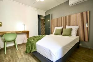 - une chambre avec un grand lit et une chaise verte dans l'établissement La Suite Azur, à Pointe-à-Pitre