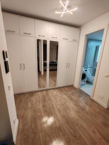 una sala de estar vacía con armarios blancos y suelo de madera. en Corporate One Room Pipera Luxury, en Bucarest