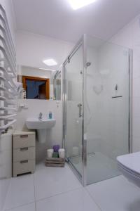 a white bathroom with a shower and a sink at Willa Grono in Krościenko