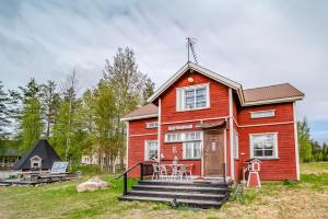 a small red house with stairs in a field at Midnight sun in Kittilä