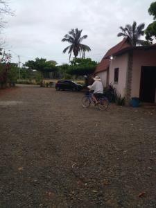 una persona montando una bicicleta delante de una casa en Cabañas Martina Surf Playa Guanico, en Pedregal