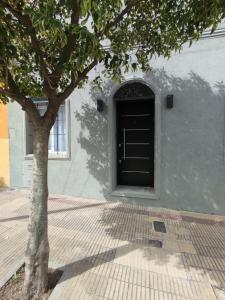 un arbre devant un bâtiment avec une porte dans l'établissement Don Quijote Tandil, à Tandil