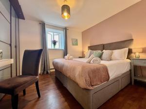 a bedroom with a bed and a chair and a window at The Orchid-Central Beeston-Private Apartment-SmartTV-Free Wi-Fi-Tram-Parking in Nottingham