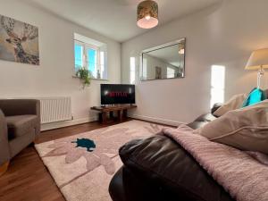a living room with a couch and a television at The Orchid-Central Beeston-Private Apartment-SmartTV-Free Wi-Fi-Tram-Parking in Nottingham