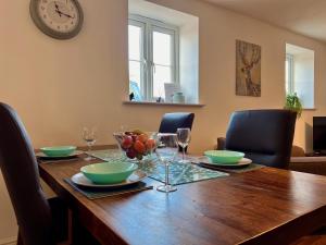 a dining room table with chairs and a clock on the wall at The Orchid-Central Beeston-Private Apartment-SmartTV-Free Wi-Fi-Tram-Parking in Nottingham