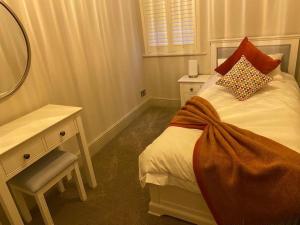 a bedroom with a bed and a desk and a mirror at 2 bedroom cottage in Stamford in Lincolnshire