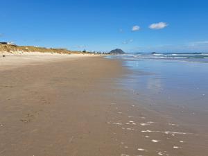 a beach with footprints in the sand and the ocean at Sunbrae Beach in Mount Maunganui