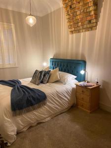 a bedroom with a bed with a blue headboard and a table at 2 bedroom cottage in Stamford in Lincolnshire