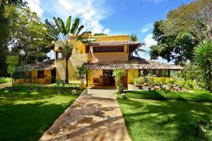 a house with a green yard with a palm tree at Casa Baiana Pousada & Aconchego in Trancoso