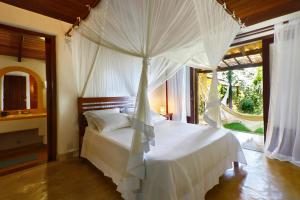 a bedroom with a white bed with a canopy at Casa Baiana Pousada & Aconchego in Trancoso