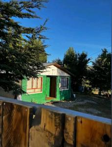 a small green house in a yard with trees at Cabaña Payun in Lonquimay