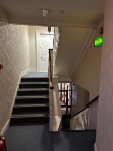 un escalier dans un bâtiment avec un panneau de sortie vert dans l'établissement Central Lisburn Accommodation, à Lisburn