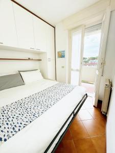 une chambre avec un lit et une grande fenêtre dans l'établissement Luminoso, Versilia, Vicino al Mare, à Marina di Carrara