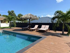 a swimming pool with chairs and umbrellas on a patio at Villa Edna in Sainte-Rose