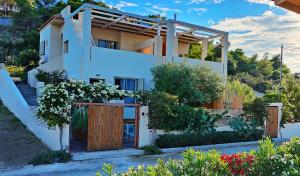 a white house with a wooden door and flowers at Casa Horizon in Porto Heli