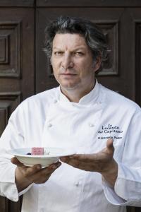 a chef is holding a plate of food at La Locanda Del Capitano in Montone