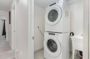 eine Waschmaschine und ein Trockner in einer weißen Waschküche in der Unterkunft 4 Bedroom Oshawa house in Oshawa