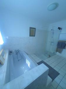 a white bathroom with a tub and a shower at Charmante maison proche plage - 5242 in Soulac-sur-Mer