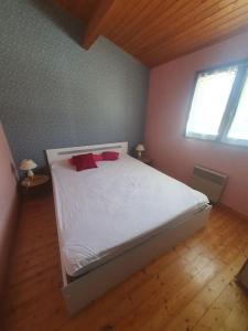 a bedroom with a white bed with two red pillows at Charmante maison proche plage - 5242 in Soulac-sur-Mer