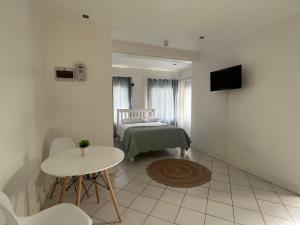 a room with a bed and a table and a television at Cavendish Suite Bachelor in Cape Town