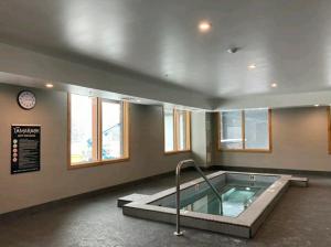 - un bain à remous dans une pièce avec une horloge et des fenêtres dans l'établissement Luxurious Vacation Apartment Mountain Scenery, à Canmore