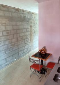 a table and a chair in a room with a brick wall at Monoambientes Chamical in Chamical